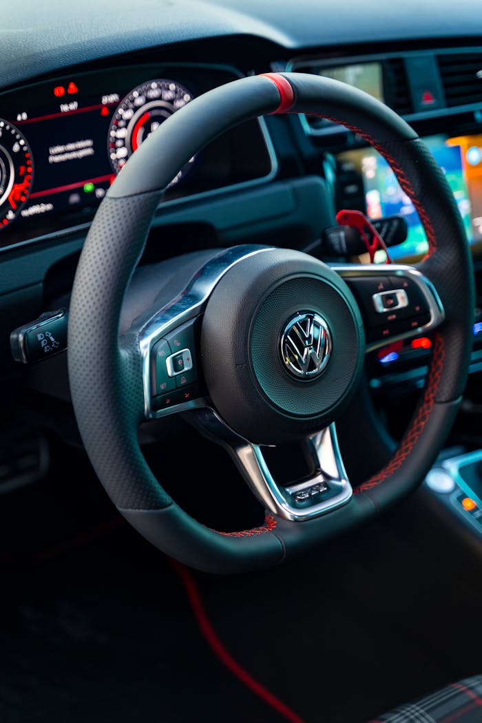 Services-02 Close-up view of a car's modern steering wheel and dashboard, showcasing technology and design.