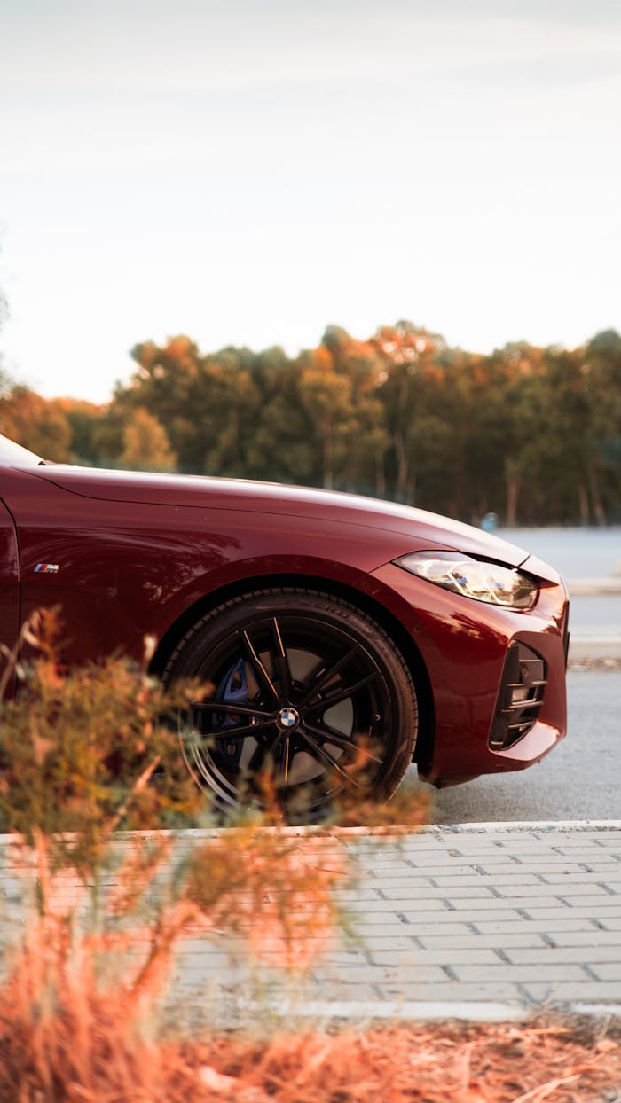 digital Side view of a red BMW sports car parked in İzmir, Türkiye, during a picturesque sunset.